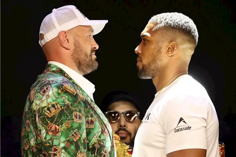 Tyson Fury en veste verte à motif de couronnes face à Anthony Joshua en chemise blanche lors d’un face-à-face